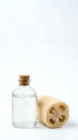 Natural spa essentials with glass bottle and loofah sponge on white background for wellness and skincare routines.
