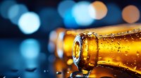 Cold amber bottle with water drops and condensation on dark background with blue bokeh lights, close up macro photography for beverage advertising.