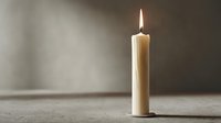 Single lit candle flame glowing on wooden surface against neutral wall background creating peaceful ambiance for meditation and relaxation concepts.