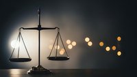 Classic brass scales of justice on wooden surface with warm bokeh lights creating atmospheric legal concept for law firms and judicial themes.