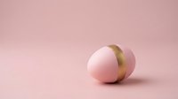 Minimalist pink egg with golden band on soft pink background for Easter holiday design and spring celebration concepts.