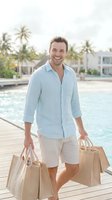 Young man with light brown hair and Caucasian ethnicity smiling while holding shopping bags on a wooden dock beside a resort pool, wearing casual light blue linen shirt and beige shorts in tropical vacation setting.