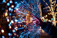 Hand touching glowing digital interface with colorful bokeh lights and illuminated trees in background creating magical nighttime atmosphere.