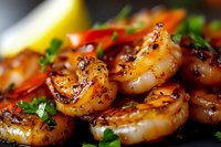 Grilled jumbo shrimp with fresh herbs, lemon and spices in macro view showing juicy texture and caramelized surface, garnished with chopped parsley and red chili.