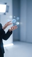 Businessperson in dark suit manipulating glowing holographic geometric shapes floating above hands in futuristic digital interface concept.