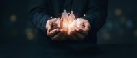 Business professional cupping hands around glowing team figures representing leadership, human resources management, employee care and corporate teamwork concepts.