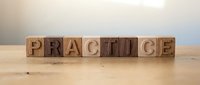 Wooden letter blocks spelling PRACTICE on natural wood surface for education and skill development concepts.