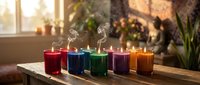 Colorful scented candles in glass holders arranged on wooden surface creating warm cozy atmosphere for relaxation meditation and home decor aromatherapy.