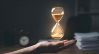 Glowing hourglass floating above open palm in dark office setting with clock and papers, symbolizing time management and deadline pressure in business.