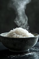 Steaming bowl of freshly cooked white rice in rustic ceramic bowl against dark background, ideal for food blogs and culinary publications.