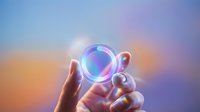 Glowing crystal sphere held in hand against colorful sunset sky gradient background, representing future vision, technology, and innovation for design projects.