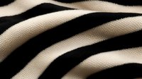 Dramatic close-up of black and white striped fabric texture showing detailed weave pattern and curved lines creating dynamic abstract composition. Suitable for backgrounds.