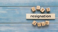 Wooden blocks spelling out resignation word on blue wooden background, symbolizing career change and professional transition decision making process.