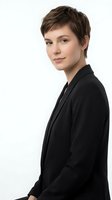 Professional young woman with short brown hair in black blazer smiling confidently on white background isolated for business and corporate design use.