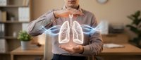 Professional man in business attire displaying glowing holographic lungs with protective gesture in modern office environment for healthcare technology concepts.