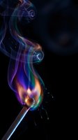 Colorful rainbow smoke rising from burning match against black background creating abstract swirls and patterns for creative design projects.