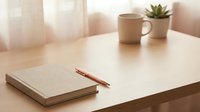 Minimalist workspace with notebook, copper pen, coffee mug and succulent plant on wooden desk. Clean home office setup for productivity and focus.