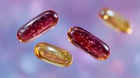 Translucent red and yellow gel capsules floating against purple background with soft bokeh effect, pharmaceutical medicine concept for healthcare and supplements.