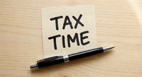Tax time reminder note with black pen on wooden desk for accounting and financial planning preparation.