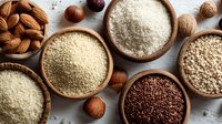 Assorted grains, seeds, and nuts in wooden bowls on rustic table, including quinoa, couscous, rice, and almonds for healthy cooking.