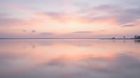 Serene lake at dawn with soft pink and purple sky reflecting on calm water surface, peaceful nature landscape for meditation and relaxation projects.