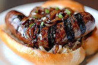 Grilled sausage with caramelized onions and fresh herbs served on soft bun, close up view showing juicy meat texture and grill marks for food service industry.