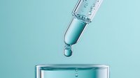 Dropper with clear liquid dropping into glass container on mint background. Close-up macro photography shows transparent substance with reflection and refraction effects.