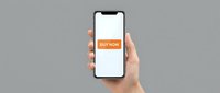 Hand holding a smartphone with an orange buy now button on screen, showcasing mobile shopping and e-commerce app interface on gray background.