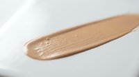 Liquid foundation makeup smear on white background showing smooth creamy texture for cosmetic and beauty product applications.