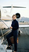Professional businesswoman boarding private jet at airport runway holding leather briefcase ready for corporate travel and luxury aviation experience.