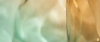 Blurred glass surface with warm golden and soft green tones creating an abstract, dreamy background suitable for design overlays.