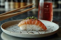 Fresh salmon nigiri sushi garnished with green onions on ceramic plate with artistic design, chopsticks and soy sauce bottle in background, macro food photography.