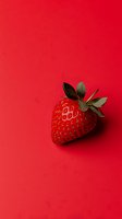 Fresh ripe strawberry with green leaves isolated on vibrant red background. Minimalist food photography with copy space for text or design elements.