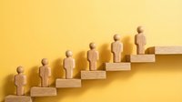 Wooden human figures ascending steps symbolizing career growth, leadership development, and business success progression on yellow background.