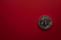 Silver bitcoin cryptocurrency coin on deep red background with copy space for financial and digital currency concept.