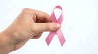 Hand holding pink awareness ribbon symbol for breast cancer support and healthcare advocacy on white background.