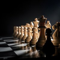 Wooden chess pieces on board with dramatic lighting showcasing strategy and competition in classic board game setup for business concepts.