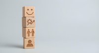Wooden blocks with human resources icons including smiley face, handshake, people and person symbols stacked vertically on white background for business concepts.