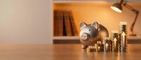 Piggy bank with stacked coins and percentage symbols representing financial growth, savings, and investment returns on wooden desk.