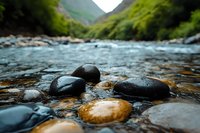 Smooth river rocks in crystal clear mountain stream with rushing water and lush green valley background, natural landscape photography for wellness and spa.