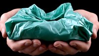 Hands gently holding crumpled turquoise surgical fabric against black background, creating dramatic contrast and highlighting texture of sterile medical material.