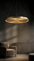 Modern circular pendant light fixture with warm LED illumination hanging above contemporary armchair in luxury interior design setting.