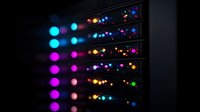 Glowing LED indicators on dark server rack equipment with colorful blue, purple and orange lights creating moody tech atmosphere. Perfect for data center concepts.