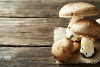 Fresh brown portobello mushrooms on rustic burlap against wooden background, natural organic produce with earthy tones and soft lighting for food photography.