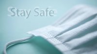 Surgical face mask on teal background with Stay Safe text, promoting health protection and virus prevention awareness.