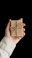 Hand holding a natural handmade soap bar tied with jute twine, isolated on transparent background. Ready for wellness, eco, and skincare product design use.
