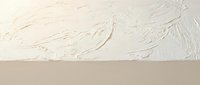 Textured cream wall surface with rough plaster finish and artistic brush strokes creating abstract patterns for interior design backgrounds.