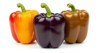 Three fresh bell peppers in red, yellow, and dark purple varieties arranged on white background, isolated and ready for culinary, food styling, recipe, and design projects.