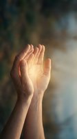 Cupped hands reaching upward with warm golden light glowing from palms, symbolizing hope, prayer, spirituality and divine connection against soft blurred background.