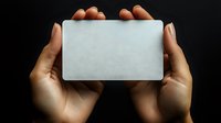 Female hands holding blank white card against dark background, dramatic lighting emphasizes empty space ready for business card or credit card mockup design.